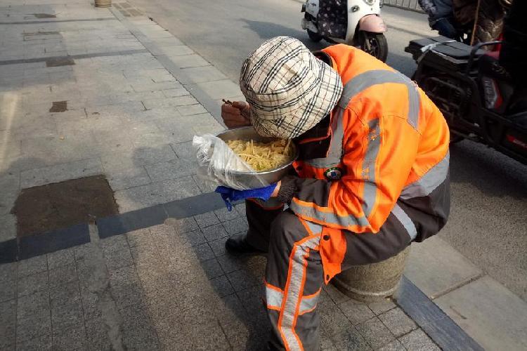 环卫工街头用脸盆吃午饭 全是面条几乎没有菜叶