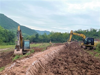 梁平区福禄镇乐园村高标准农田建设现场,工人驾驶挖掘机在平整农田.