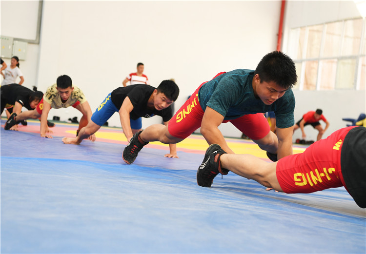 4月10日,红狮中学摔跤班的教练李学奎(中)在指导学生进行摔跤训练